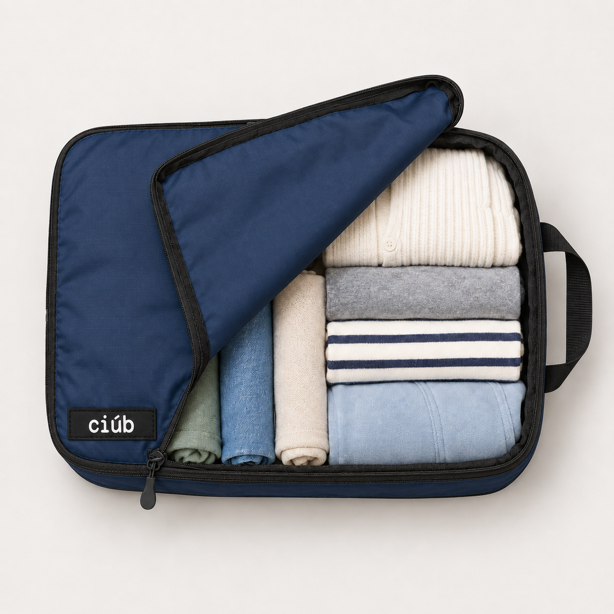 Navy ciúb extra-large compression packing cube unzipped to show folded jumpers, shirts and t-shirts packed inside for travel