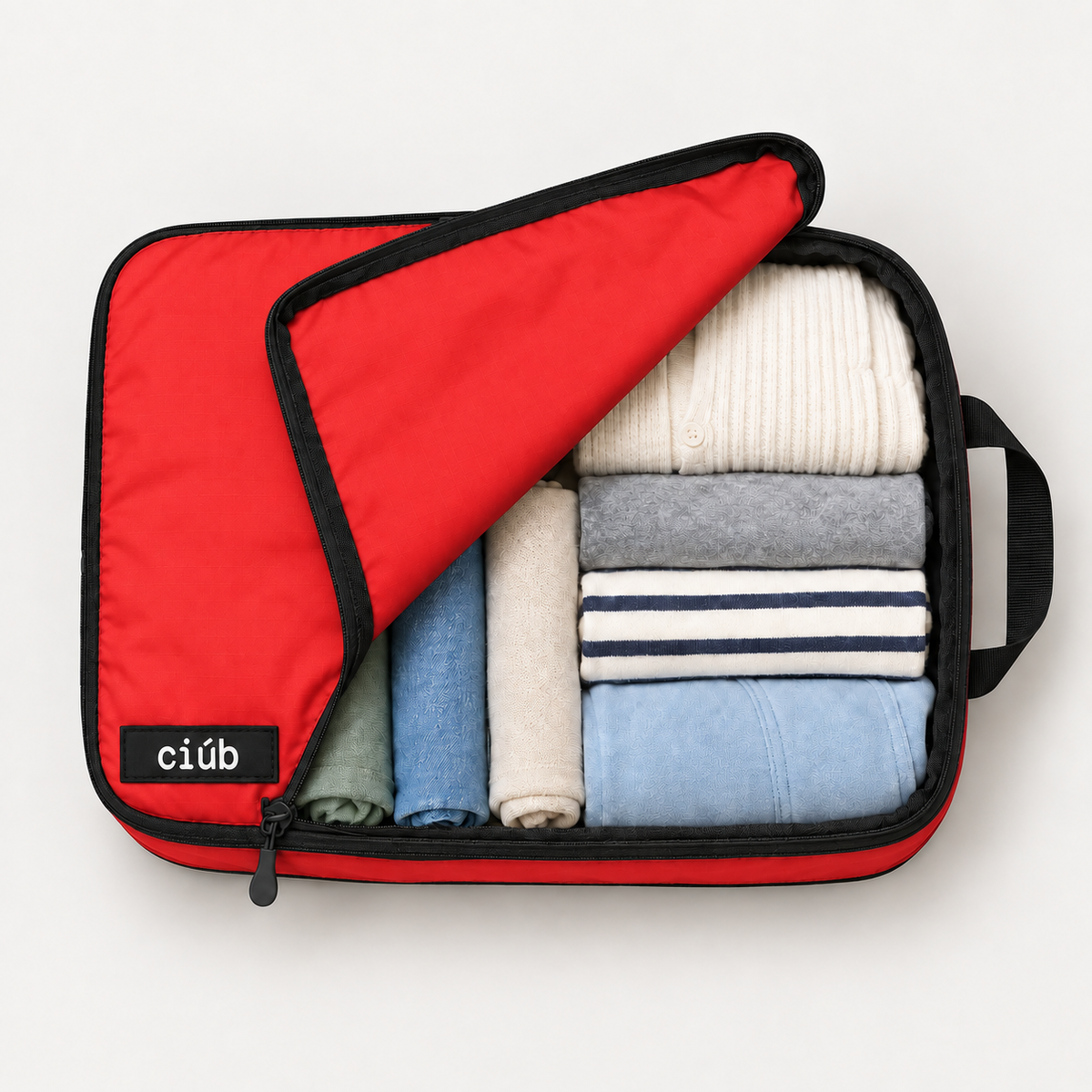 Red ciúb extra-large compression packing cube unzipped to show folded jumpers, shirts and t-shirts packed inside for travel