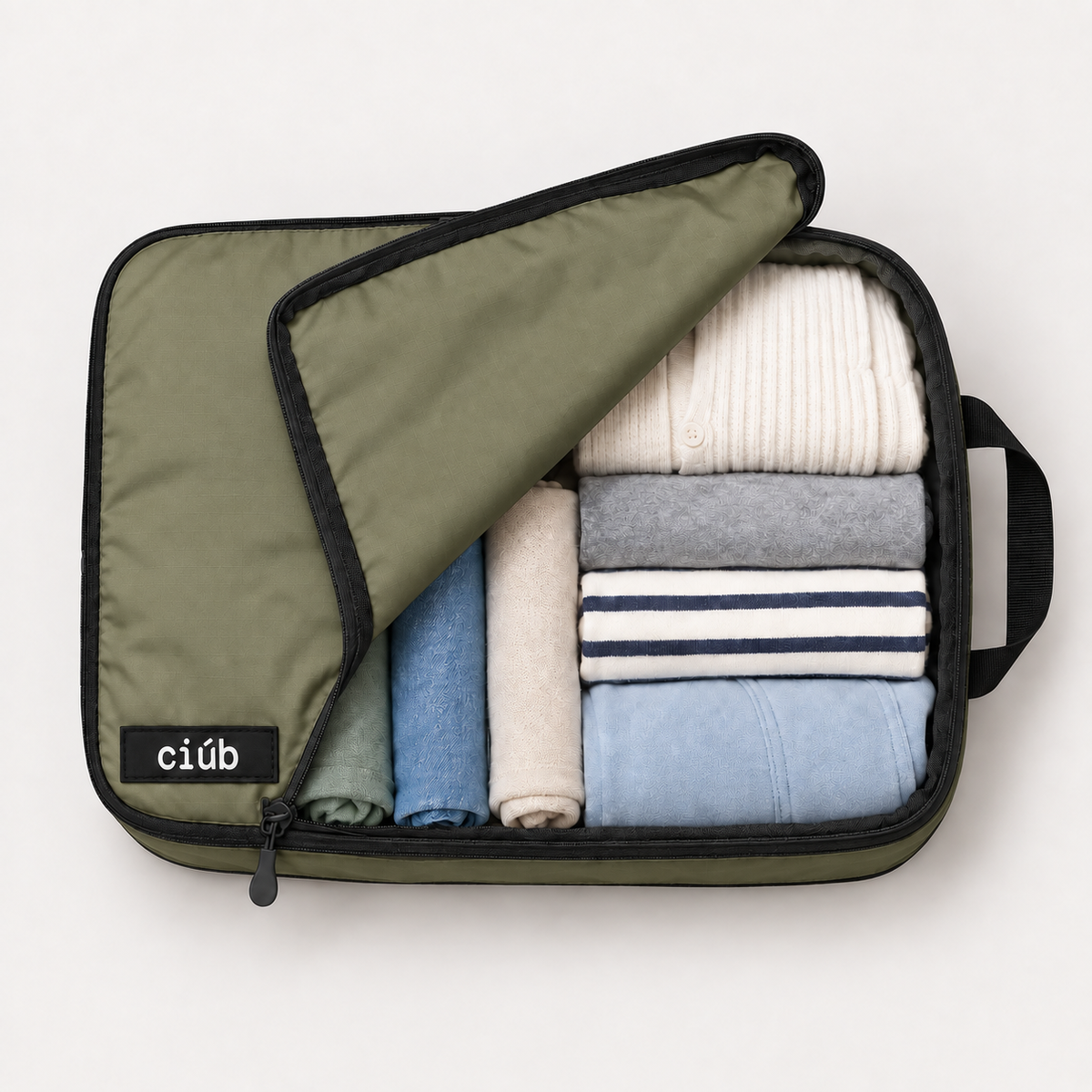 Khaki ciúb extra-large compression packing cube unzipped to show folded jumpers, shirts and t-shirts packed inside for travel
